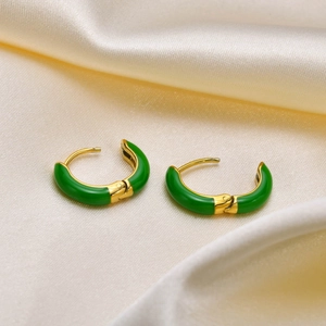 Detail of green enamel finish on gold-plated stainless steel hoop earrings on satin