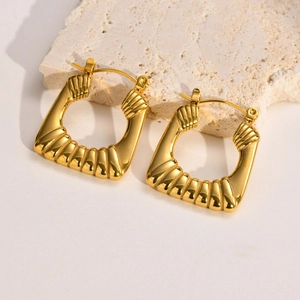 Detailed macro view of gold U-shaped earrings with textured spiral ribbing on stone