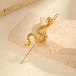 Détail d'une boucle d'oreille serpent dorée avec texture écailles sur pierre naturelle