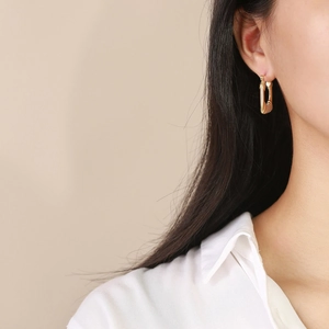 Elegant gold U-shaped rectangular earrings with textured stripes on model