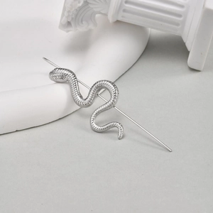 Détail de piercing industriel serpent argenté avec texture écailles sur plateau blanc