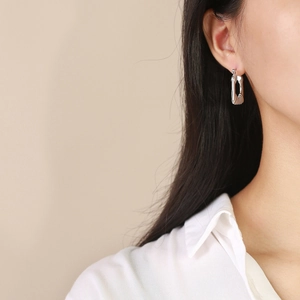 Macro shot of silver rectangular U-shaped hoop earrings with textured horizontal ridges
