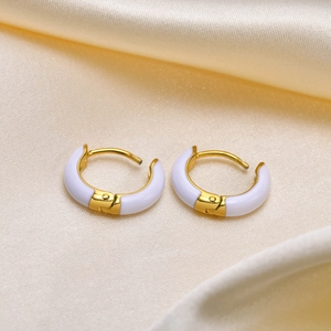 Elegant gold stainless steel hoop earrings with white enamel inlay on silk background