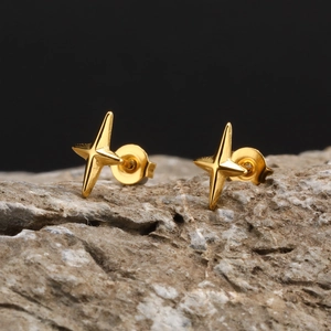 Close-up of golden four-pointed star stud earrings on a natural grey stone background