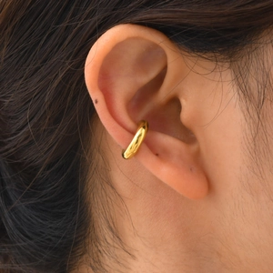 Nahaufnahme eines minimalistischen 18K vergoldeten C-Ohrklemmen-Modells am Ohr