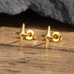 Polished gold stainless steel star stud earrings on a natural wood and rock background