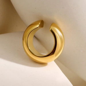 Polierte 18K Gold C-förmige Edelstahl-Ohrmanschette auf minimalistischem Stein-Hintergrund