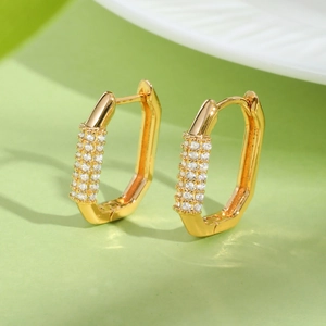 Close-up of gold geometric huggie earrings with four rows of paved white zircons