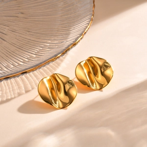 Detailed view of irregular wavy gold stud earrings with polished hammered texture finish