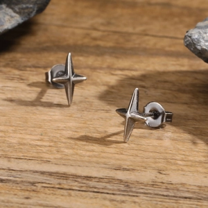 Macro shot of punk style stainless steel four-pointed star earrings on a dark stone base