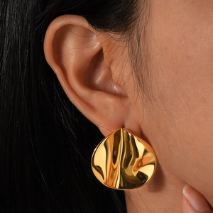 Golden irregular wavy geometric stud earrings in stainless steel on a female model