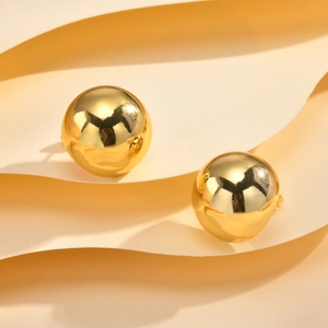 Close-up of polished gold spherical stud earrings with mirror finish on wavy paper