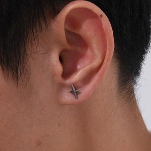 Close-up of punk style stainless steel four-pointed star stud earring on a male ear