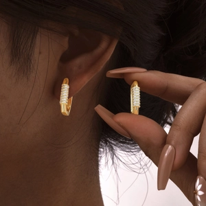 Macro detail of wide gold-plated hoop earrings featuring micro-pave cubic zirconia stones