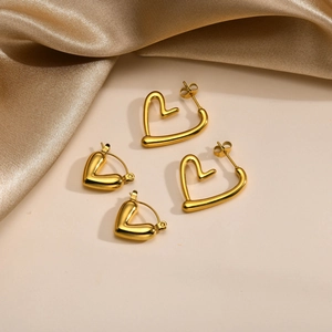 Two pairs of polished gold stainless steel heart hoop earrings on satin background