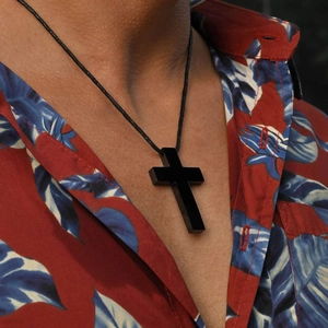Minimalistische schwarze Kreuzkette für Herren mit Wachskordel an Model mit Blumenhemd