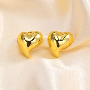 Close-up of golden heart-shaped earrings on champagne silk fabric with elegant highlights