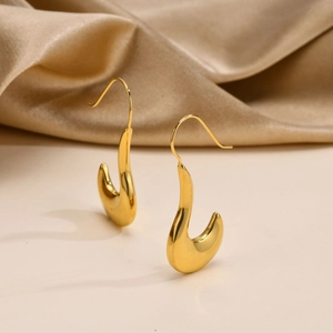 Close-up of elegant gold U-shaped twist earrings on luxury champagne silk backdrop
