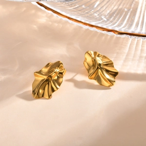 Detailed close-up of golden stainless steel stud earrings with irregular folded design