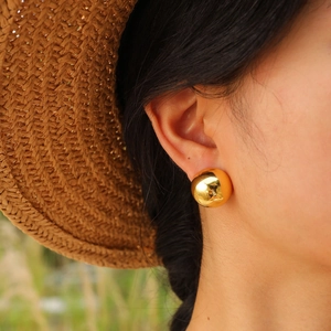 Chic gold high-polished spherical stud earrings for women shown on a model outdoors