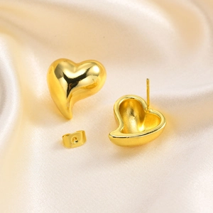 Elegant 3D heart-shaped gold studs with a mirror-polished finish on silk fabric