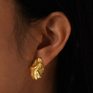 Macro shot of gold-plated geometric earrings with irregular leaf-like crinkled texture