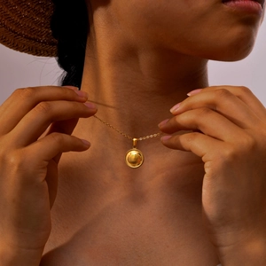 Close-up of golden shell pendant necklace with twisted rope edge on a model
