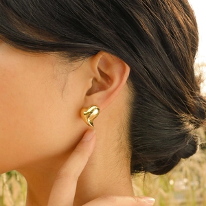 Elegant gold heart-shaped stud earrings for women with a polished mirror finish on model