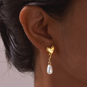 Boucles d'oreilles cœur en acier doré avec perle goutte portées par modèle