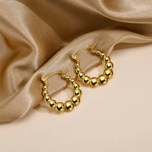 Detailed macro view of 18K gold beaded hoop earrings with gradient mirror finish