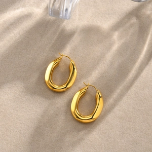 Detailed macro shot of glossy gold U-shaped earrings on a textured sand background