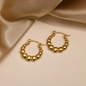 Detailed view of gold beaded hoop earrings with graduated polished metal spheres