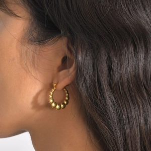 Close-up of gold beaded hoop earrings worn by a model for a chic and stylish look