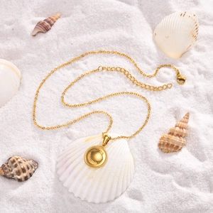 Golden stainless steel shell pendant necklace on white sand with marine decorations