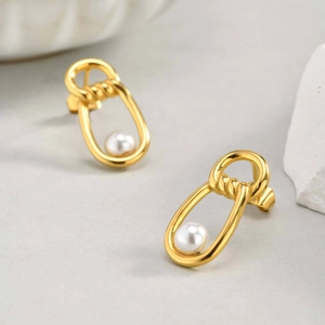 Elegant gold oval earrings with infinity knot detail and a white pearl on a clean surface