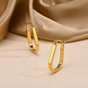 Detailed view of gold U-shaped earrings with textured finish on champagne silk fabric