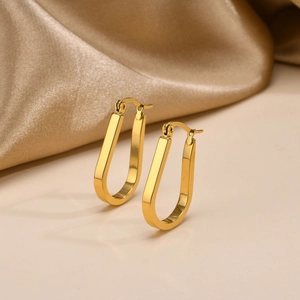 Close-up of golden U-shaped hoop earrings on elegant champagne gold silk background