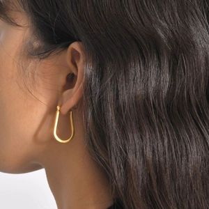 Close-up of a model wearing a U-shaped gold-plated twist earring with polished finish