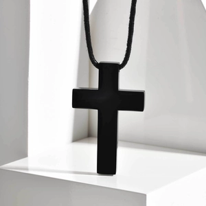 Makroaufnahme eines minimalistischen schwarzen Edelstahl-Kreuzanhängers am Wachsband