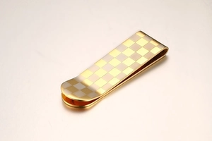 Detailed macro view of golden stainless steel money clip with classic checkerboard pattern