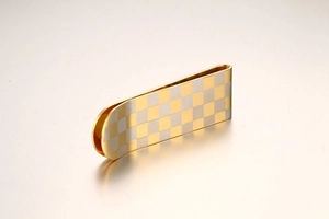 Macro shot of gold and silver checkerboard pattern on luxury stainless steel money clip