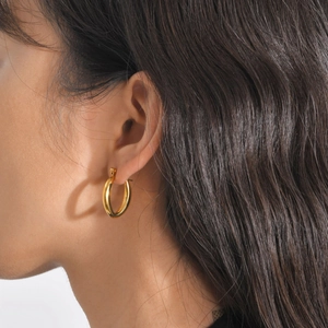 Close-up of minimalist gold chunky hoop earrings worn by a model for a modern look