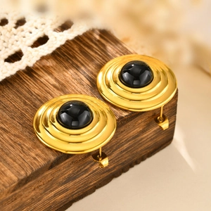 Dettaglio orecchini vintage in oro con onice nera su blocco di legno e pizzo