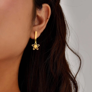 Gold stainless steel floral drop earrings worn by model with minimalist design