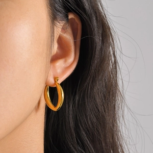 Close-up of chunky gold hoop earrings with polished finish worn by a model