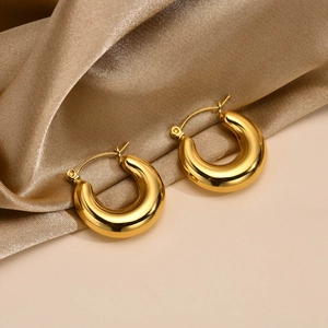 Detail shot of chunky gold hoop earrings with polished finish on champagne satin fabric