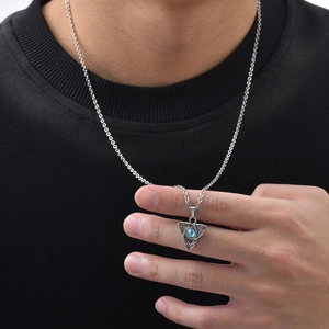 Macro shot of silver Celtic Triquetra triangle necklace with blue moonstone on male hand