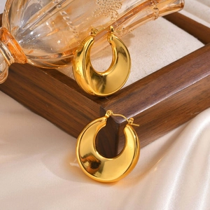 Close-up of chunky gold-plated hoop earrings with polished mirror finish on silk