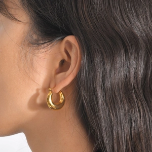 Close-up of woman wearing chunky gold U-shaped hoop earrings with a high-polished mirror finish