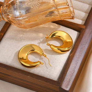 Polished gold-plated stainless steel chunky C-shaped hoop earrings on a tray
